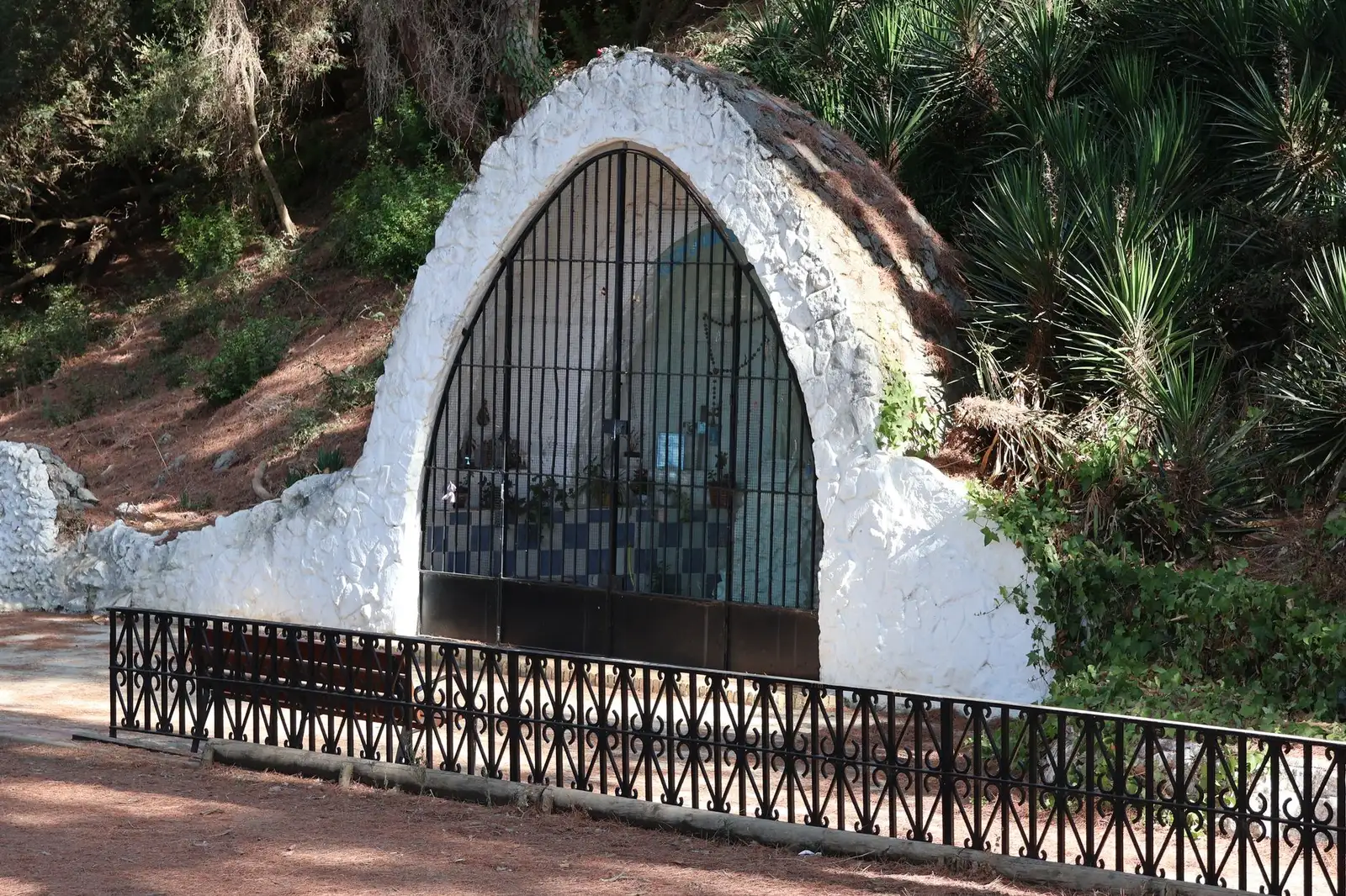 Explore a peaceful religious grotto shrine amidst the lush forest in Puerto Real, Spain.