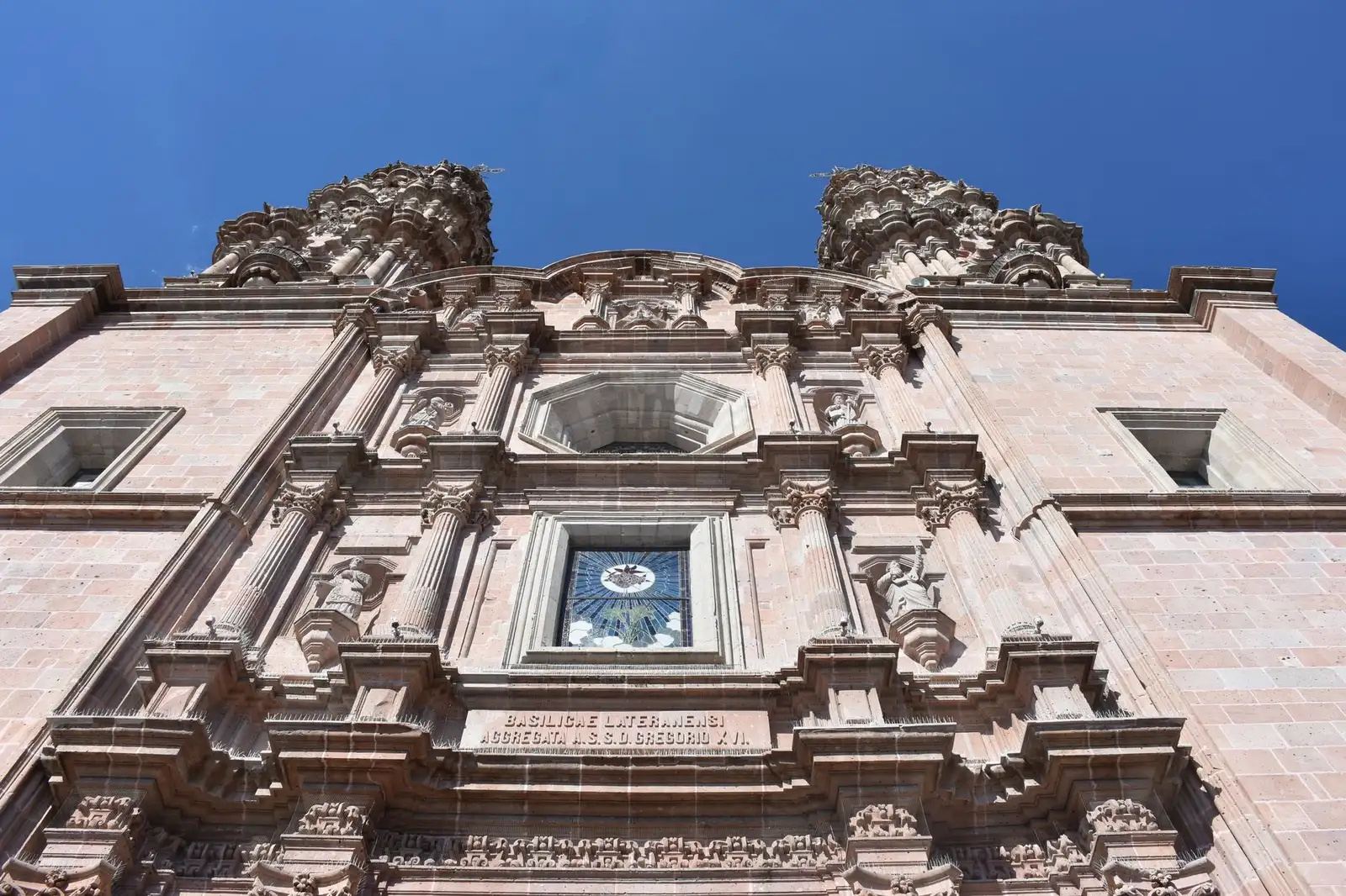 Detailed facade of the Basilica in San Juan de los Lagos, Jalisco, under a vibrant blue sky.