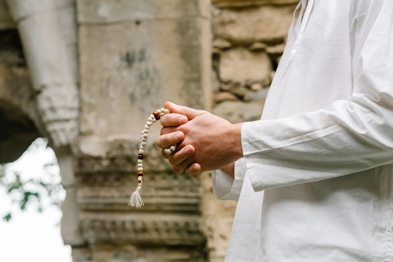 Close-up of hands holding prayer beads, symbolizing spirituality and faith.